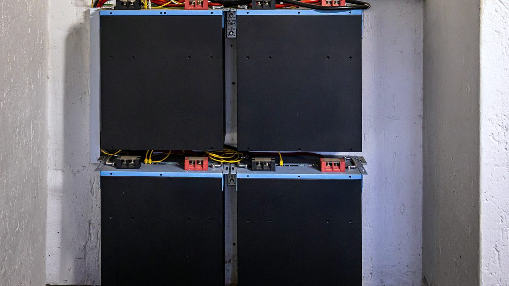 An inverter and a stack of home battery modules installed on a wall.